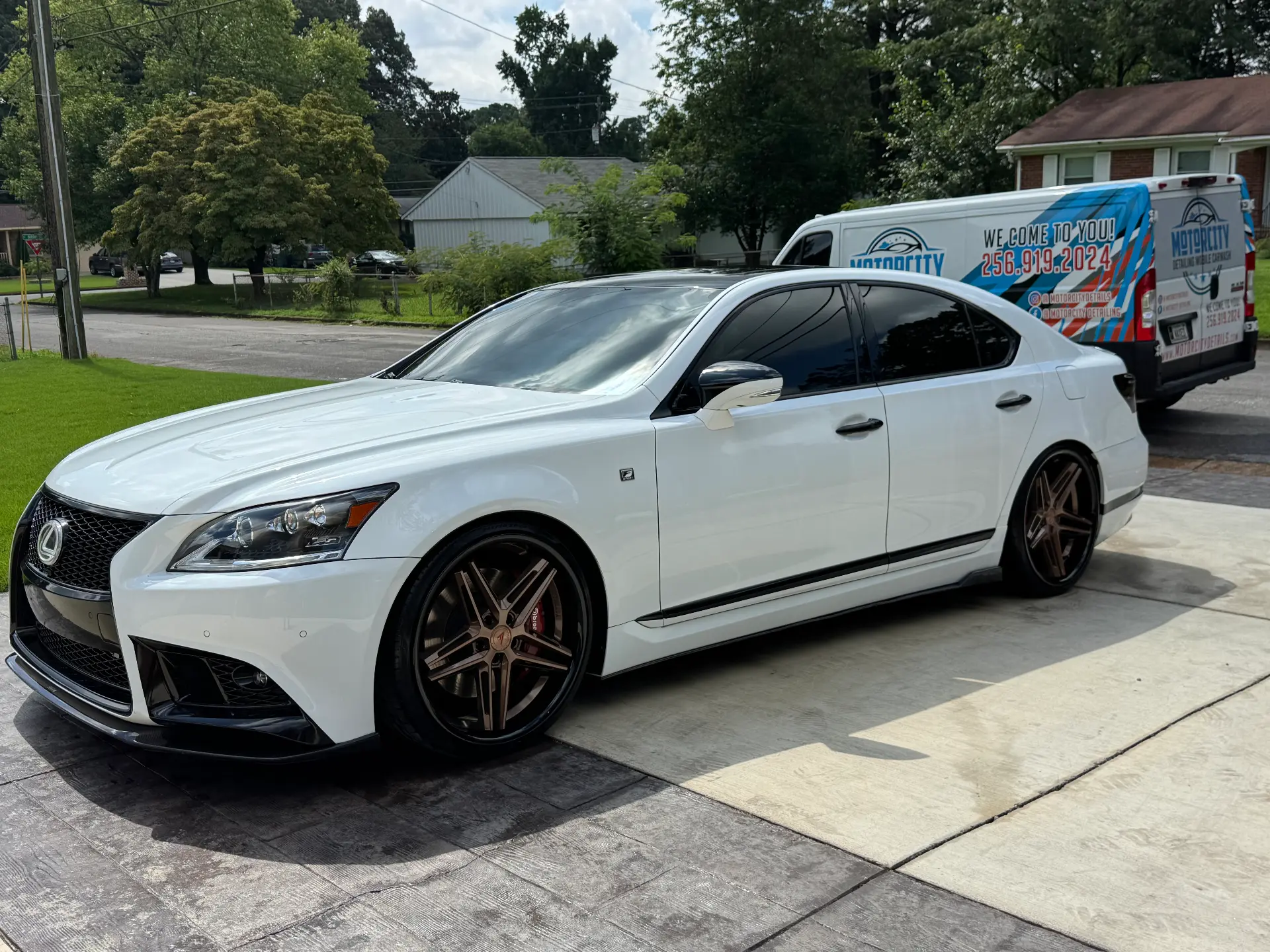 Mobile car detailing on a white Lexus LS sedan in a driveway