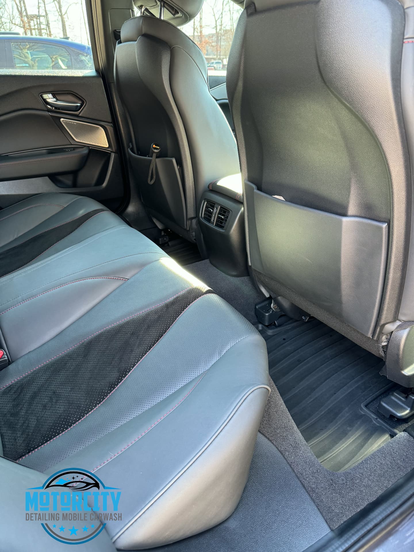 Rear leather seating and floor cleaned after a full interior detail