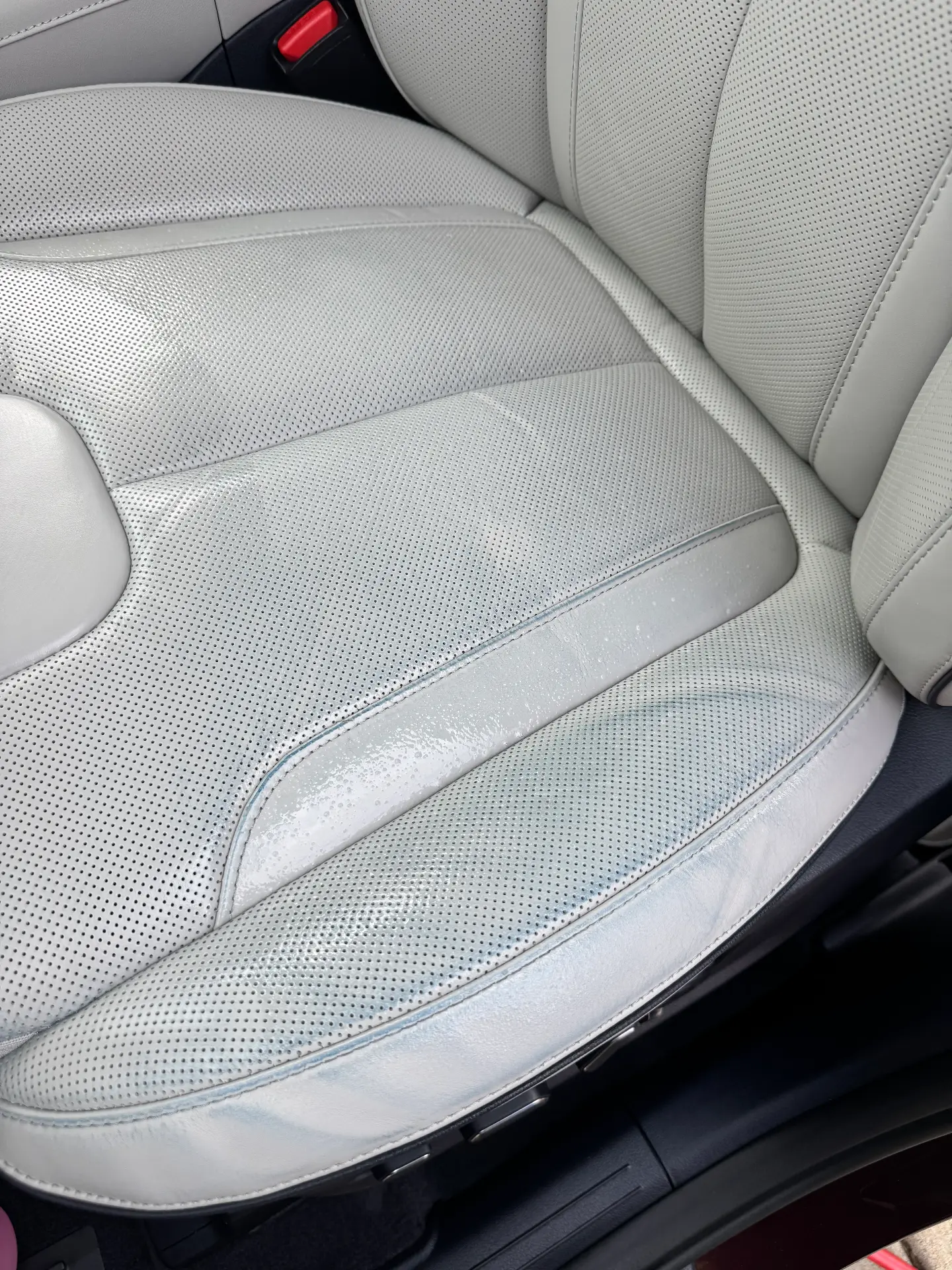 Light leather seat mid-clean with cleaning solution still on the surface